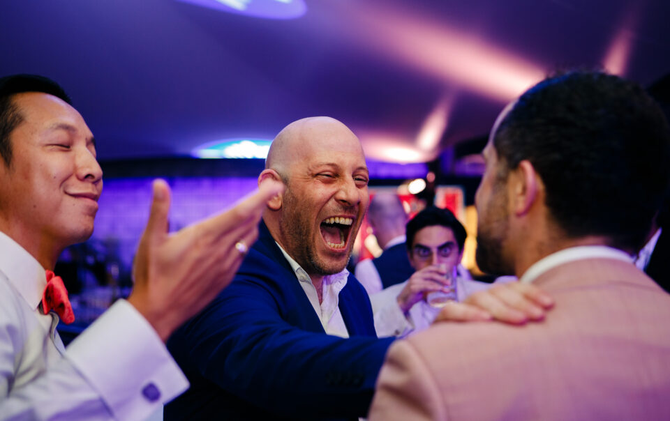 Men laughing and joking at a wedding reception in Thao Dien, Vietnam.