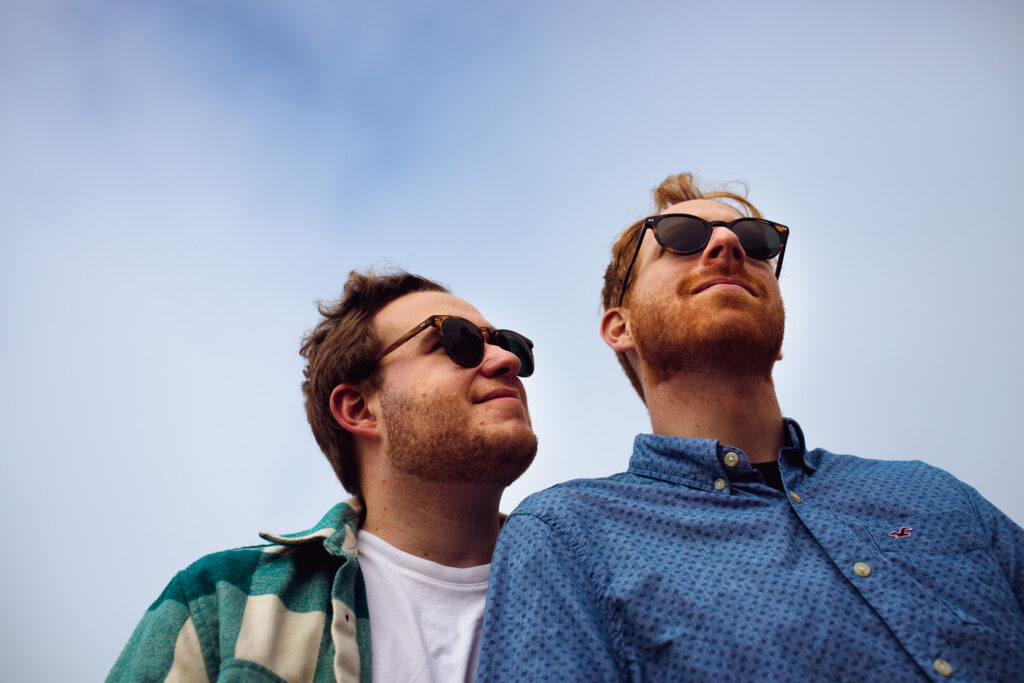 LGBTQ+ couple with a blue sky behind them during their Brighton engagement session