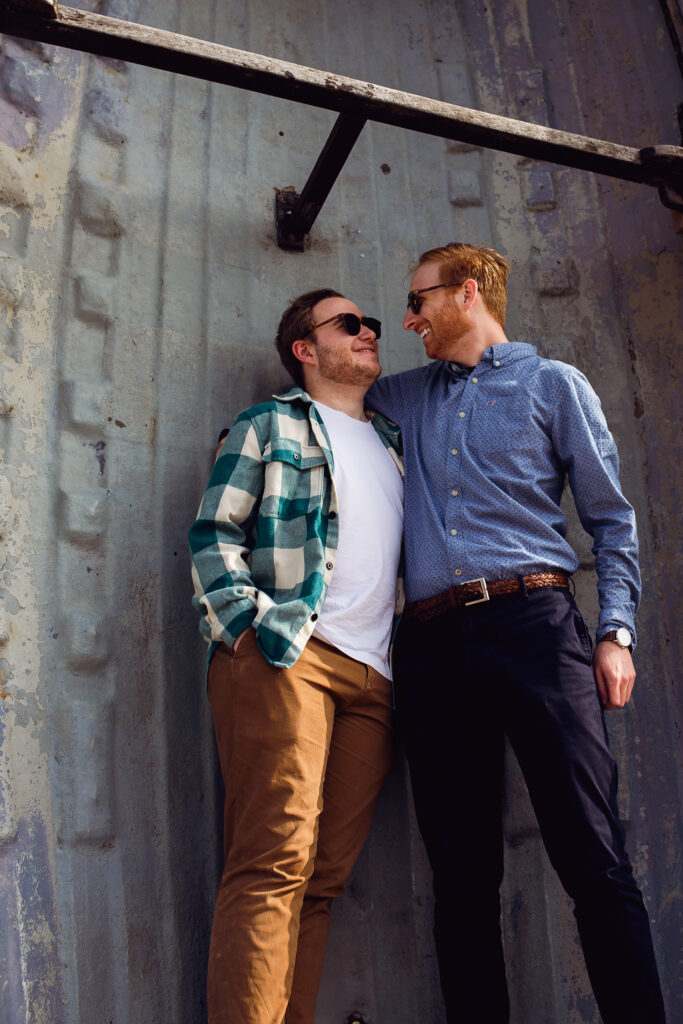 Engagement portrait of an LGBTQ+ couple looking at each other and smiling