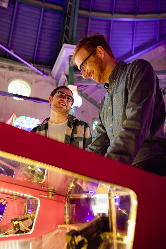 LGBTQ+ couple looking at each other and playing games at the arcade on Brighton pier