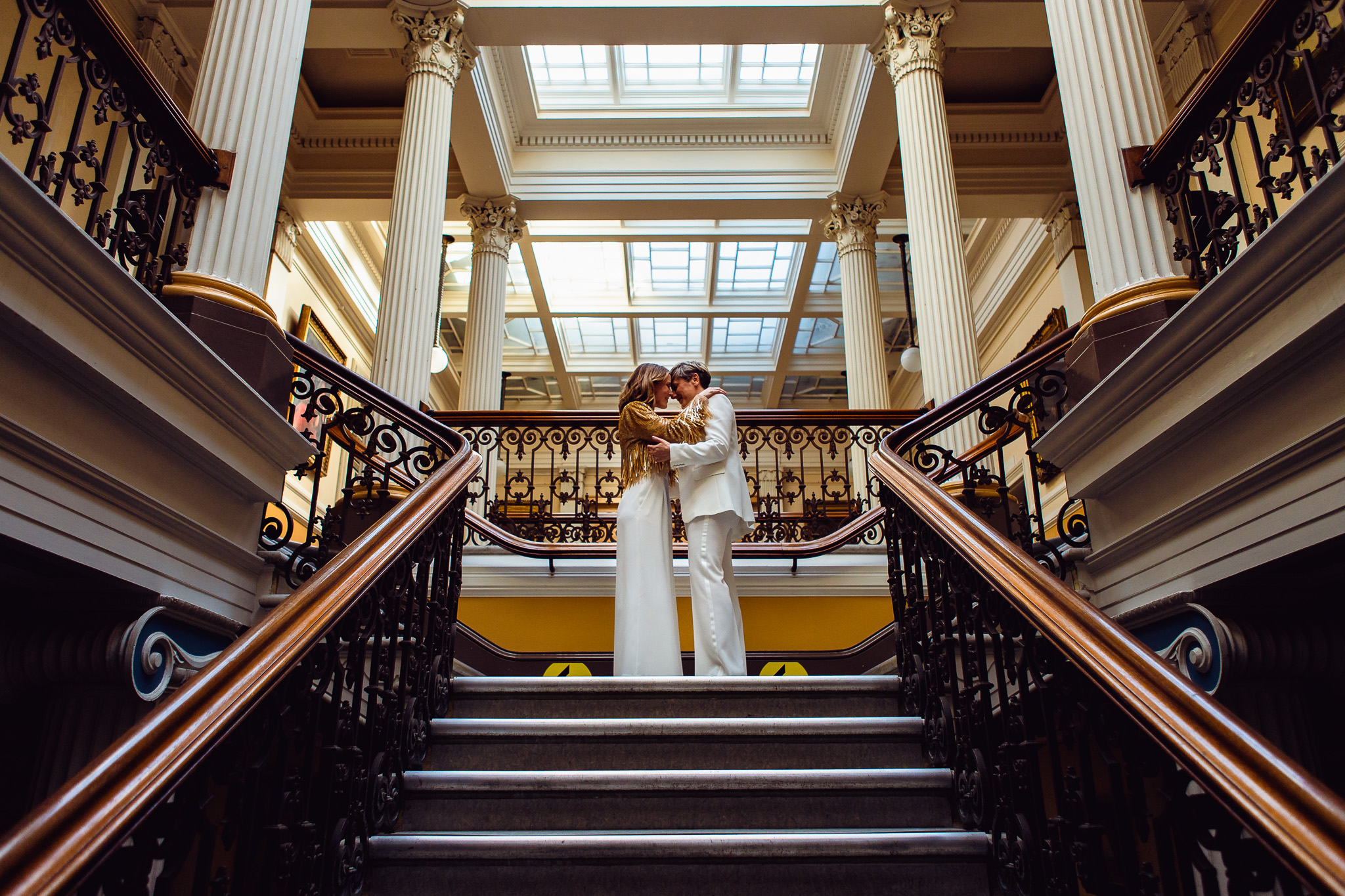 Gemma and Natalie stand facing each other on top of the stairs after their ceremony at Brighton Town Hall.