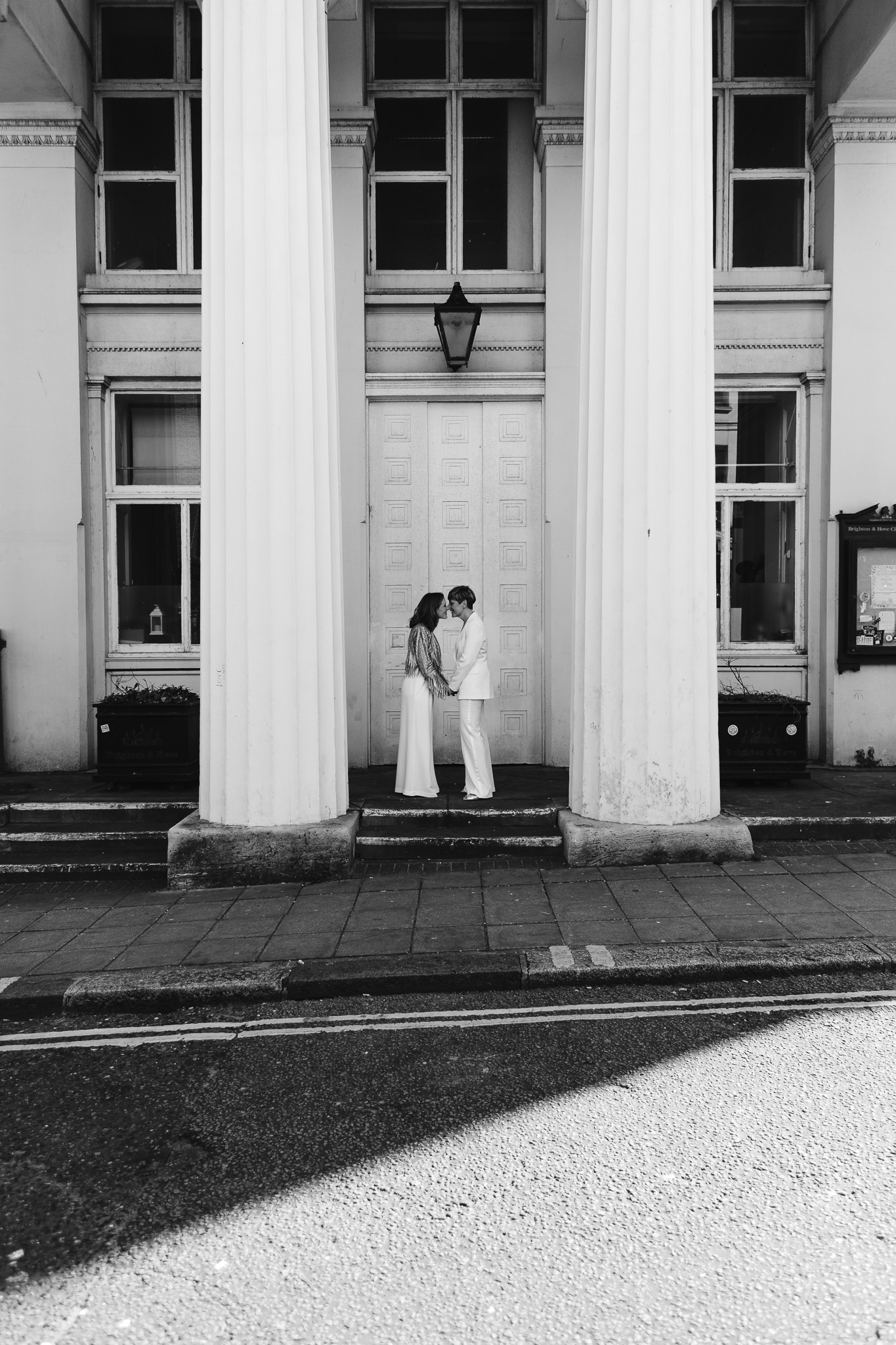 Gemma and Natalie hold hands and kiss outside Brighton Town Hall during their couple portraits.