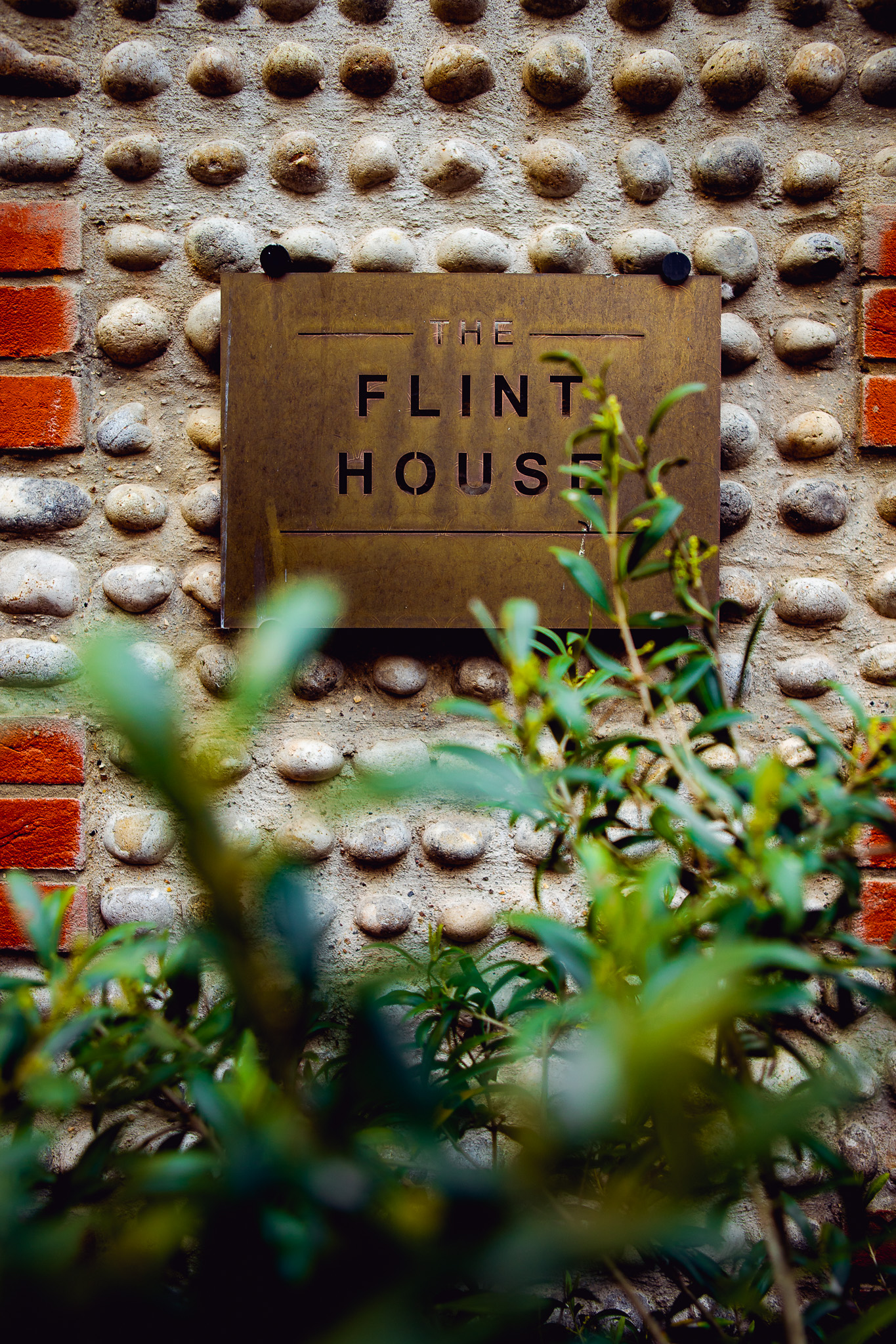 The Flint House sign on a cobbled wall in the Brighton lanes.