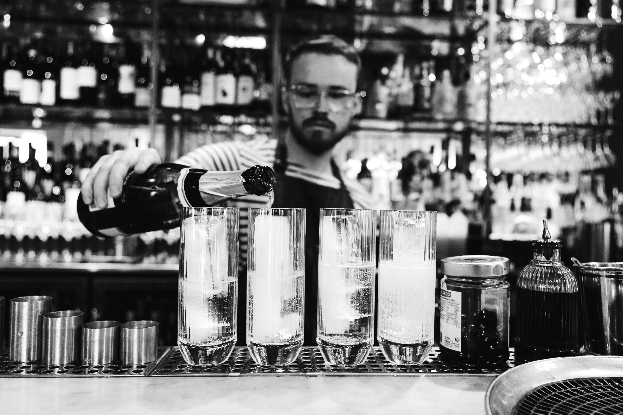 A bartender pours champagne over ice into four tall glasses during a wedding reception at the Flint House.