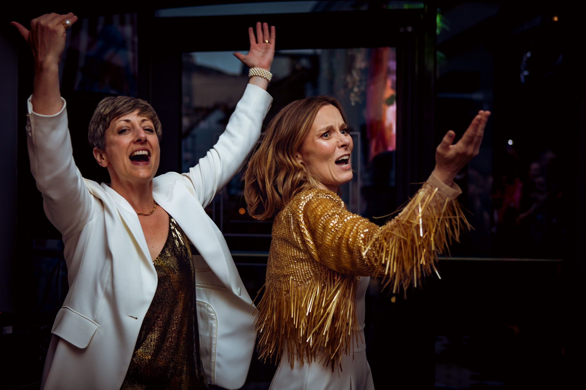 Gemma and Natalie shout and gesture for guests to dance at their wedding reception during their first dance.